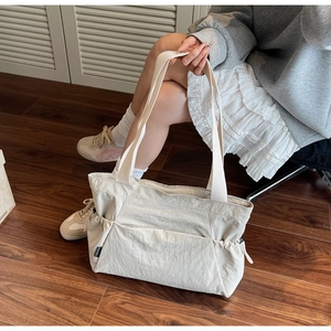 Detail of canvas tote bag showing side drawstring pocket and wide shoulder strap