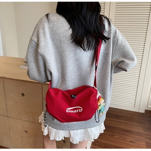 Detail of red canvas crossbody bag featuring BANATU logo and cute cartoon girl charm