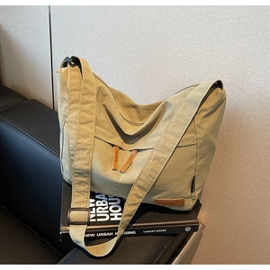 Vue détaillée du sac bandoulière en toile vert olive avec logo en cuir et poches zippées