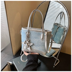 Détail du sac cabas en jean bleu clair avec poignées argentées et bordure métallique