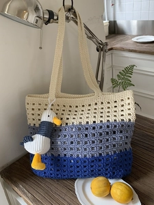 Three-color patchwork knitted mesh tote bag with a cute plush pendant in a kitchen setting