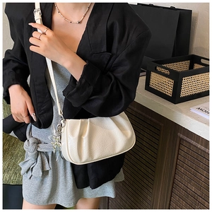 Détail d'un sac nuage plissé blanc avec texture cuir et breloque en métal argenté