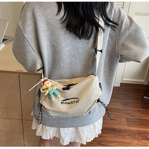 Detail of light beige canvas dumpling bag with adjustable strap and cute charm