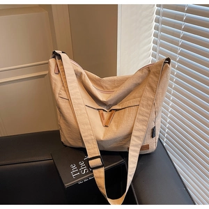 Détail du sac cabas beige en toile avec bandoulière large et surpiqûres en V en cuir de qualité