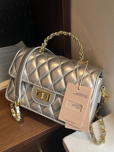 Silver quilted leather crossbody bag with gold rotating lock and chain strap on display