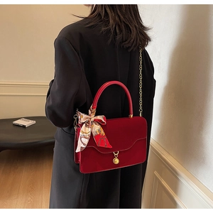 Detail of red bridal handbag with decorative printed silk scarf and gold chain strap