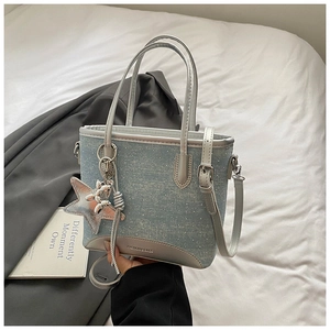 Détail du sac seau en denim bleu clair avec clous argentés et logo fashion bags