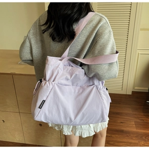 Detail of lavender canvas tote bag showing the qihuanmao side label and wide strap
