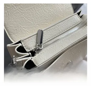 Détail du sac bandoulière blanc crème avec texture en cuir froissé et garniture argentée