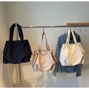 Hanging display showing minimalist tote bags in black, beige, and khaki with side knots