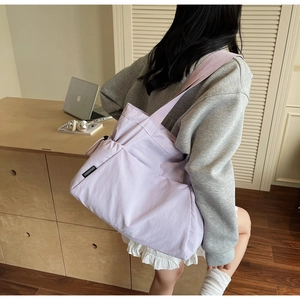 Detail of lavender nylon tote bag showing brand tag and spacious interior for daily use