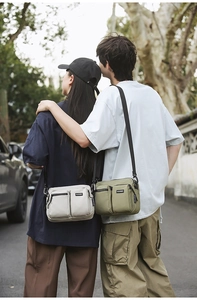 Outdoor crossbody bag in cream and olive nylon, featuring dual zip pockets and adjustable strap