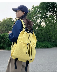 Detail of yellow water-resistant drawstring backpack with black straps and TUTIIE logo