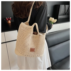 Détail du sac cabas en maille beige montrant la texture ajourée et le patch en cuir