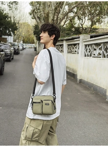 Detail view of olive nylon crossbody bag with multi-pocket design on male model outdoors