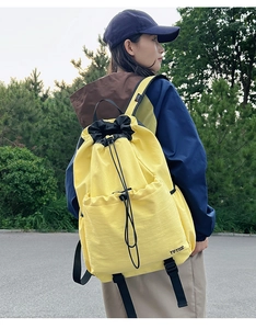 Outdoor shot of a yellow drawstring sports backpack with waterproof material and front pocket
