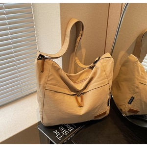 Gros plan du sac fourre-tout beige en toile montrant la texture plissée et la bandoulière