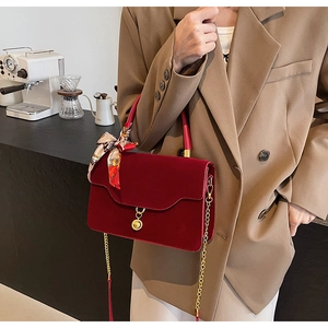Detail of burgundy wedding handbag with golden chain strap and silk scarf handle