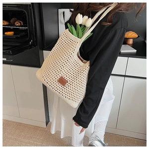 Dettaglio della borsa tote beige tessuta a mano con patch logo in pelle su trama di cotone