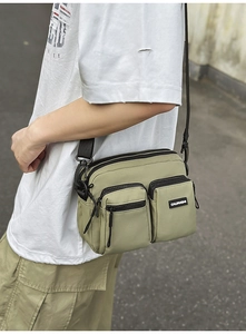 Close-up of green nylon crossbody bag showing multiple pockets and adjustable strap