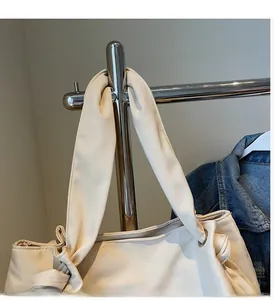 Detail of off-white canvas tote bag featuring wide knotted handles and metal eyelet rings