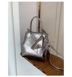 Macro view of silver metallic pleated texture with cylindrical handle and mini pouch