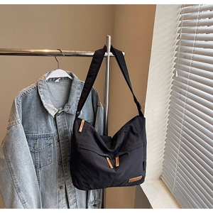 Détail du sac bandoulière en toile noire imperméable avec fermetures en cuir