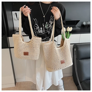 Dettaglio della borsa tote in paglia intrecciata con motivi traforati e toppa logo in ecopelle