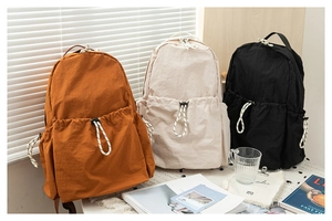 Detailed comparison of three drawstring backpacks in caramel, off-white, and black fabric