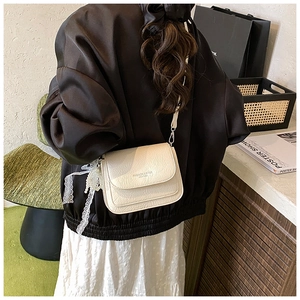 Détail d'un sac bandoulière en cuir crème avec texture plissée et breloque en perles