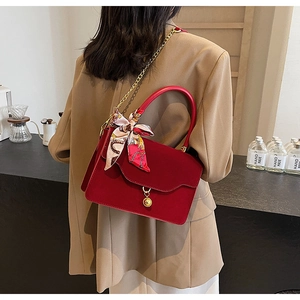 Detail of red bridal handbag featuring a colorful silk scarf handle and gold chain strap