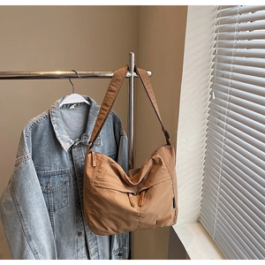 Détail d'un grand sac fourre-tout en toile marron avec plis décoratifs sur un support