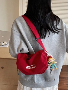 Red commuter crossbody bag with BANATU logo and cute doll pendant detail for women