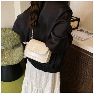Détail du sac bandoulière crème avec nœud en dentelle et texture cuir haut de gamme