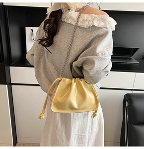 Detail of yellow glossy leather cloud bag showing textured pleats and silver chain strap