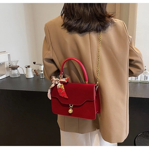 Red velvet wedding handbag with gold chain strap and decorative silk scarf on the handle