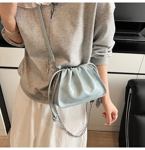 Detail of light blue patent leather pleated cloud bag with silver chain and logo