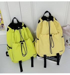 Detail of water-resistant drawstring backpacks in neon green and yellow colors