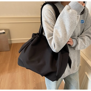 Detail of a large black tote bag with unique side knot ribbon and durable nylon texture