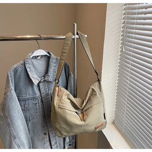 Détail du sac en toile kaki avec écusson en cuir et bandoulière large réglable