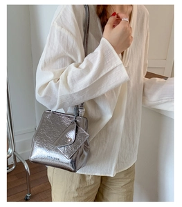 Detail of metallic silver crossbody bag with pleated leather and triangle flap pocket