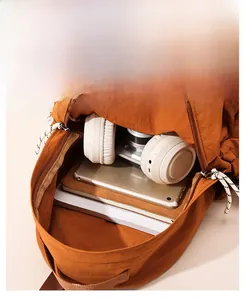 Spacious interior of a burnt orange nylon backpack holding a tablet, camera, and headphones