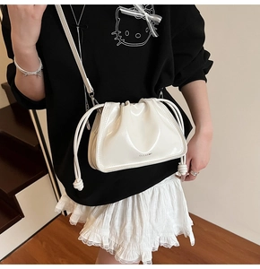Detailed view of the shiny white pleated bucket bag with brand logo and thin strap