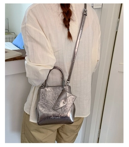 Silver metallic pleated handbag with adjustable strap and mini coin pouch on a model