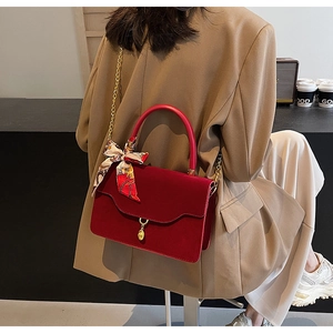 Detail of a dark red matte bridal handbag with gold chain and floral silk scarf