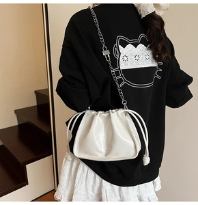 Detail of a creamy white cloud-shaped bucket bag with drawstring and silver chain strap