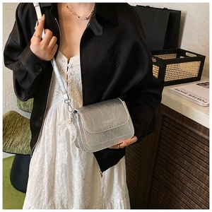 Détail du sac bandoulière argenté texturé avec breloque élégante en perles et dentelle