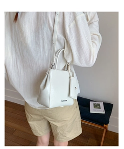 Close-up of white lychee texture PU leather handbag with metallic logo and mini coin purse