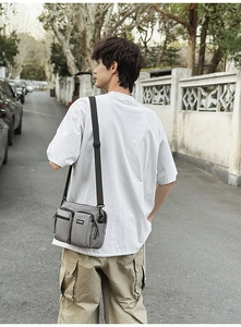 Outdoor life shot of grey multi-pocket canvas crossbody bag with adjustable strap