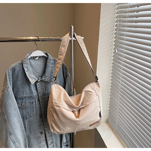 Vue détaillée d'un sac cabas beige en toile avec des accents en cuir marron sur cintre